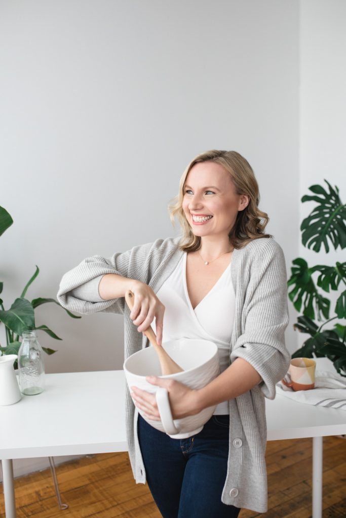 Lady smiling and stirring with a wooden spoon and bowl