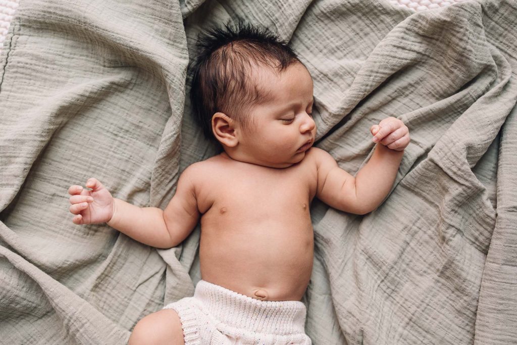 Baby sleeping on sage swaddle with arms out by a Montreal Photographer